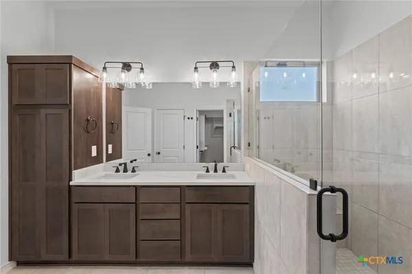 a bathroom with a double vanity sink mirror and shower