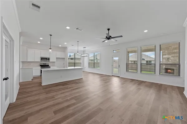 a large kitchen with stainless steel appliances kitchen island a large counter top and a wooden floors