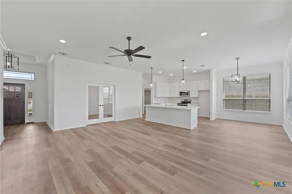 a view of an empty room with kitchen and window