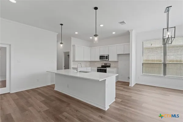 a large white kitchen with lots of counter space sink and refrigerator