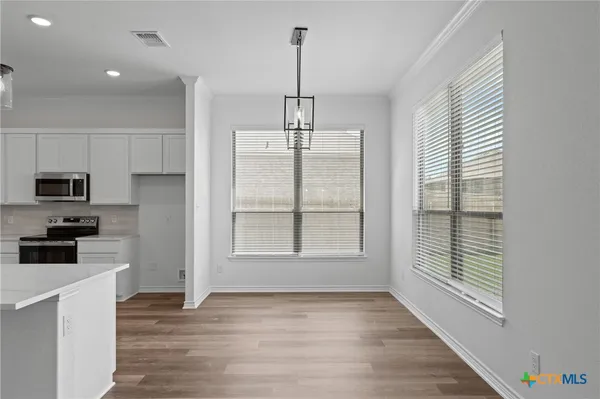 a kitchen with stainless steel appliances granite countertop a stove a refrigerator a sink and a window with wooden floor
