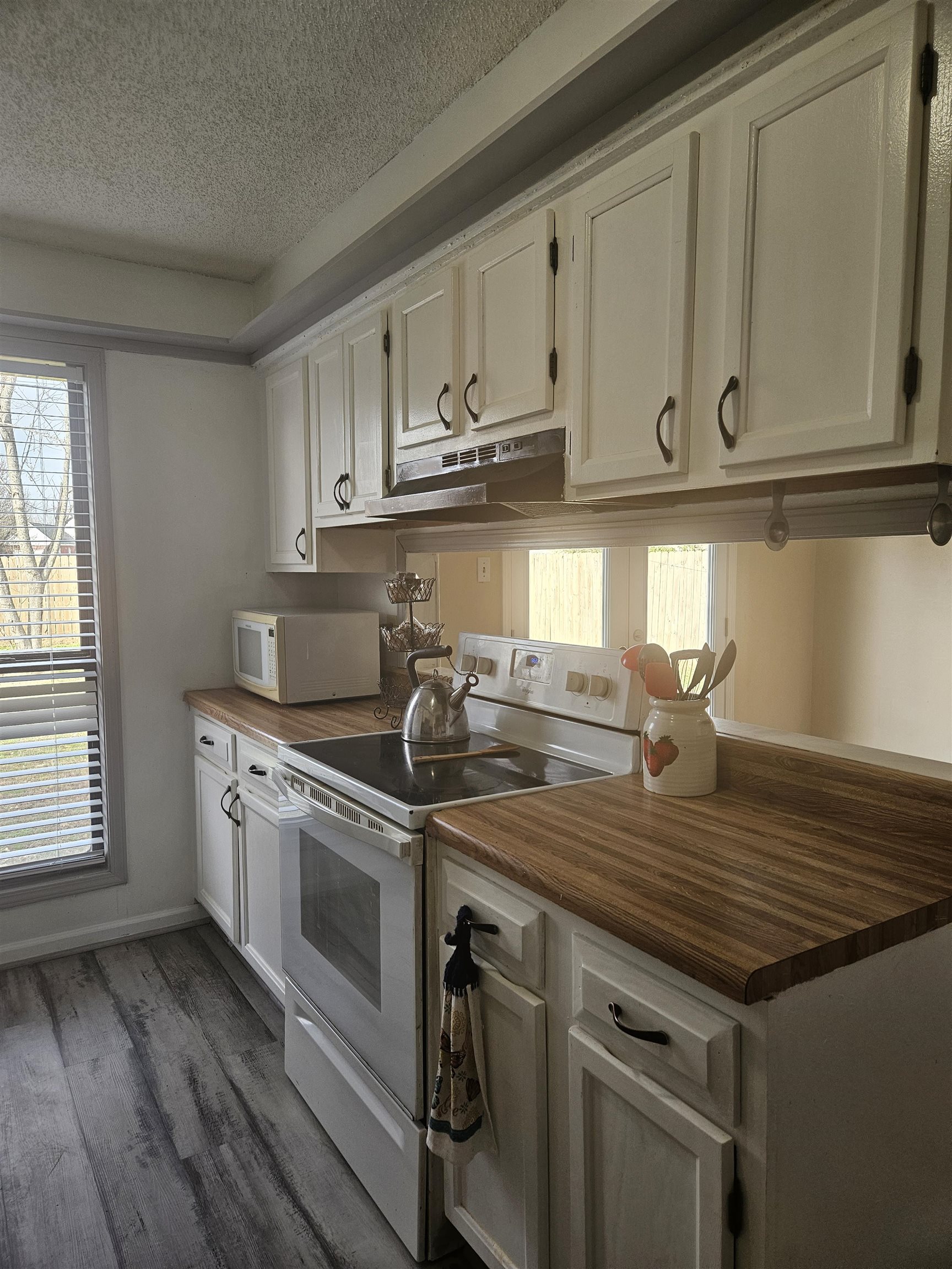 4262 Water Briar Road Millington, TN 38053 - Photo 8 of 21 Kitchen featuring wooden counters, a textured ceiling, wood finished floors, white appliances, and under cabinet range hood