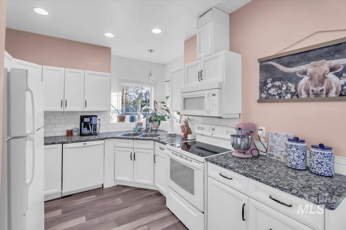 15046 Burger Lane Caldwell, ID 83607 - Photo 1 of 31 Kitchen with white appliances, white cabinetry, light wood-style floors, dark stone countertops, and recessed lighting