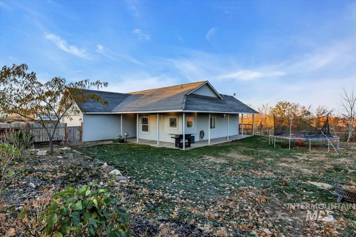 15046 Burger Lane Caldwell, ID 83607 - Photo 23 of 31 Rear view of house with a trampoline, a patio, roof with shingles, and a fenced backyard