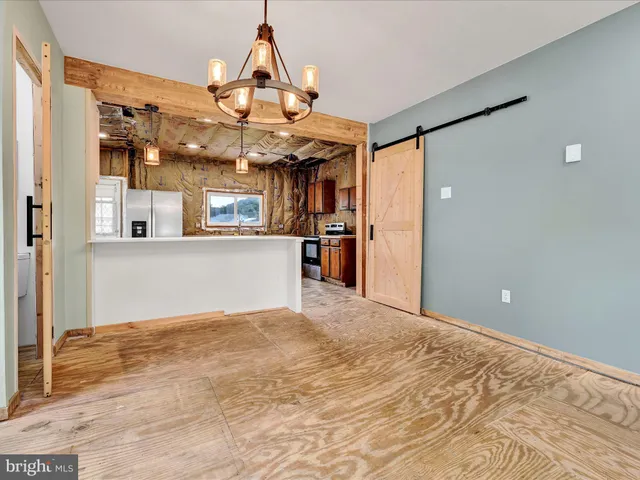 a view of a big room with wooden floor and kitchen view