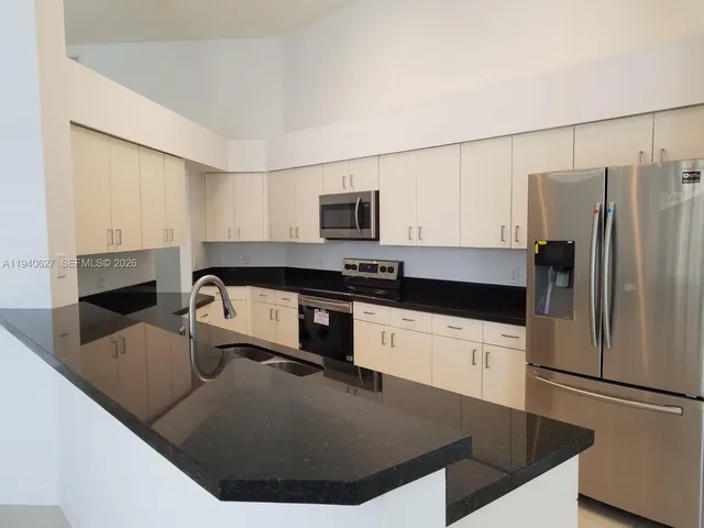 a kitchen with kitchen island a stove a sink and a refrigerator