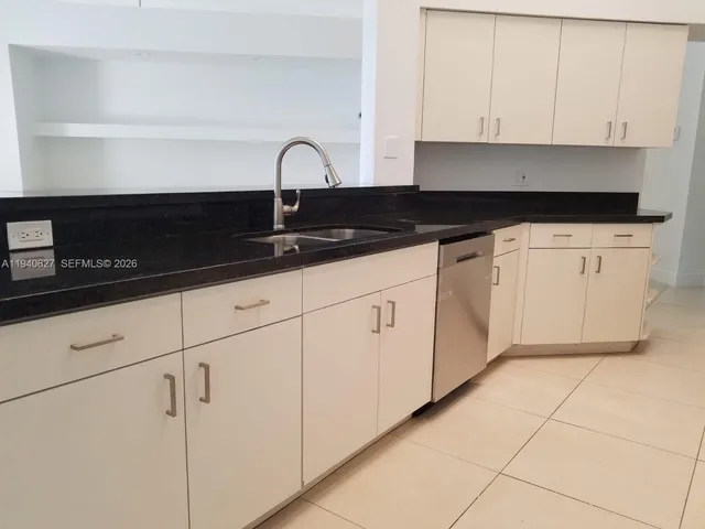 a kitchen with granite countertop white cabinets and black appliances