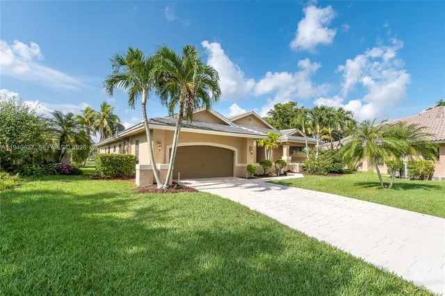 a view of a house with a yard and palm trees