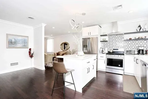 a large kitchen with kitchen island a stove a sink dishwasher and white cabinets with wooden floor