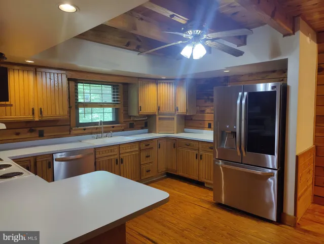 a kitchen with a refrigerator a sink cabinets and wooden floor