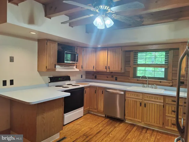 a kitchen with stainless steel appliances granite countertop a sink dishwasher stove and white countertops with wooden floor