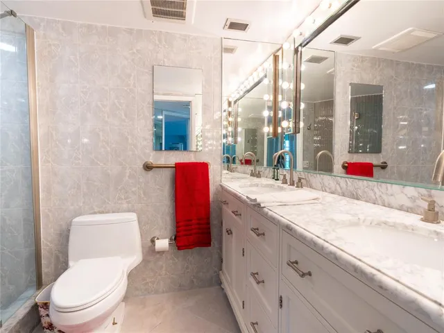a bathroom with a granite countertop toilet sink and mirror