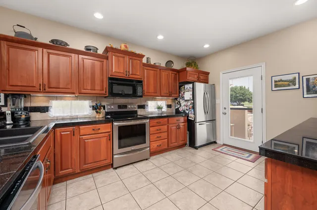 a kitchen with stainless steel appliances granite countertop a refrigerator stove top oven and sink