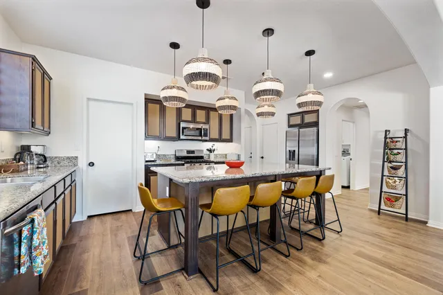 a kitchen with stainless steel appliances kitchen island granite countertop a table chairs sink and cabinets