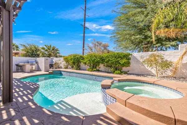 a view of backyard with swimming pool and seating space