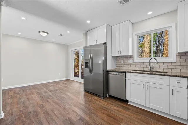 a kitchen with stainless steel appliances granite countertop a refrigerator sink and white cabinets