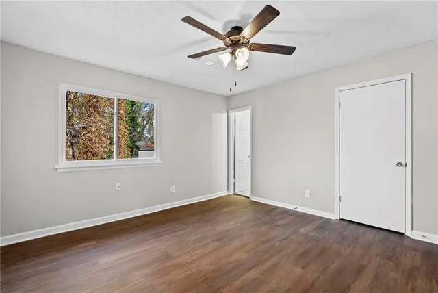 a view of an empty room with a window and wooden floor