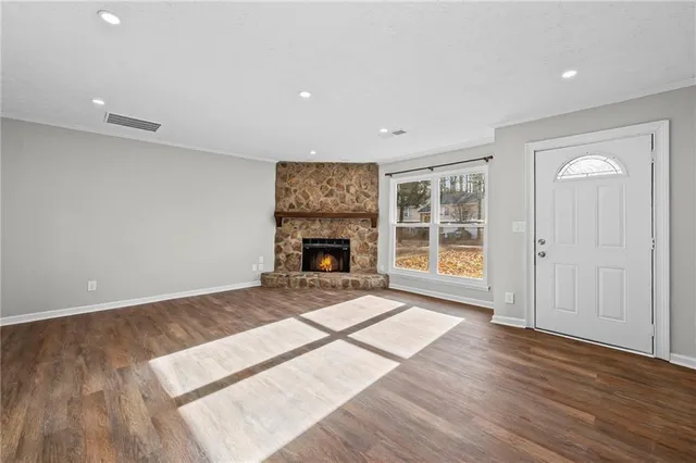 an empty room with wooden floor fireplace and windows