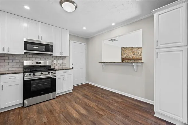 a kitchen with granite countertop a stove a sink and a microwave