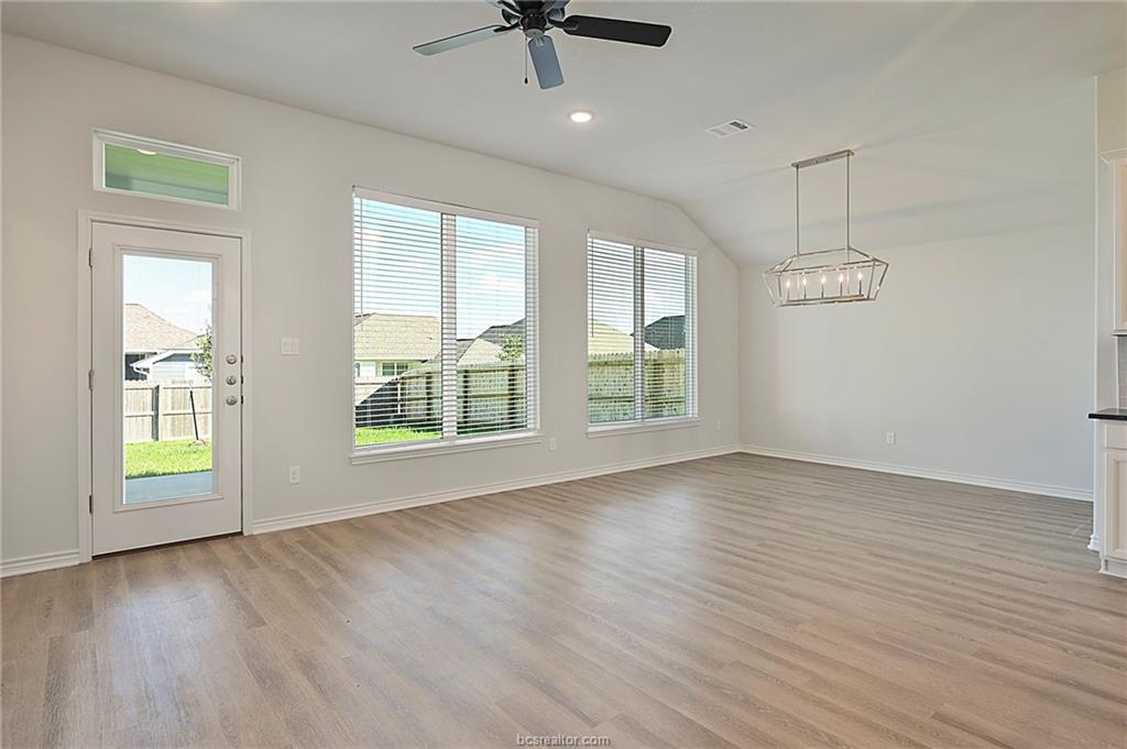 3124 Tarleton Court Bryan, TX 77808 - Photo 3 of 22 an empty room with wooden floor chandelier fan and windows