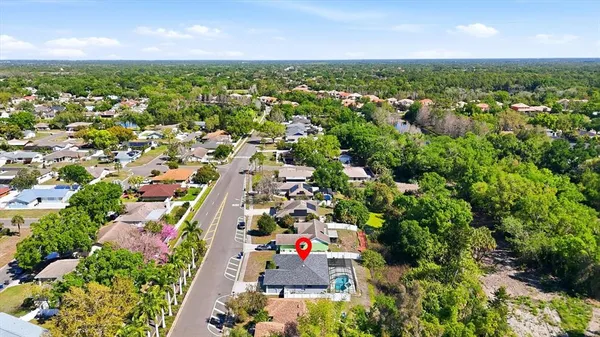 an aerial view of residential houses with outdoor space and trees