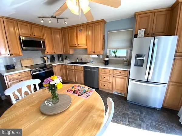 a kitchen with stainless steel appliances granite countertop a sink a microwave a refrigerator a stove a dining table and chairs