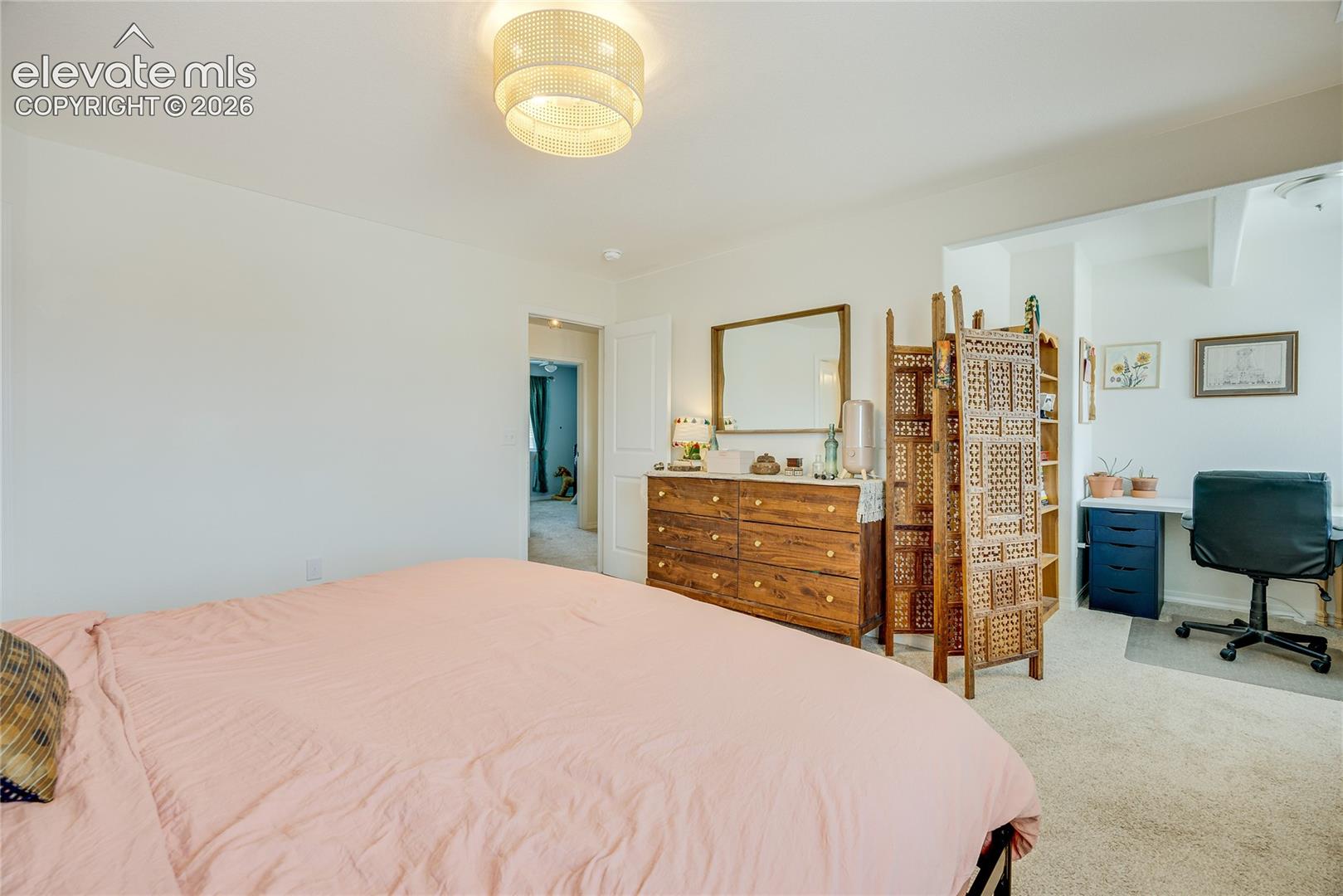 10993 Avena Road Peyton, CO 80831 - Photo 8 of 42 Bedroom featuring a built-in recessed area, overhead flush mount lighting, light-toned carpeting, and a doorway to an additional space