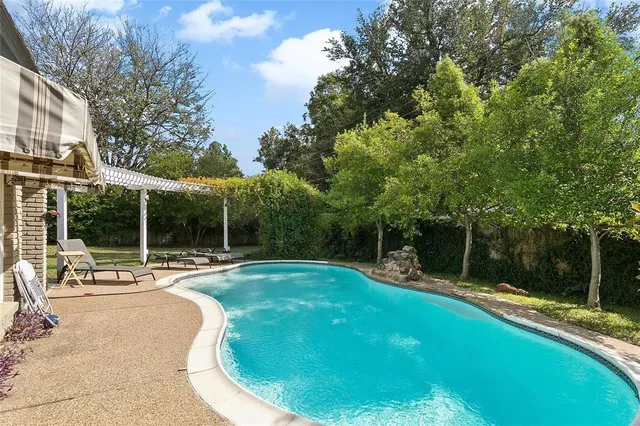 a view of a swimming pool with a patio and a yard