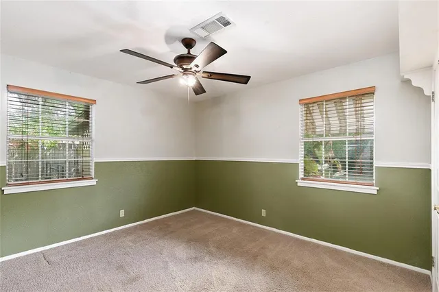 an empty room with a window and ceiling fan