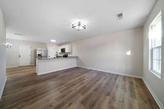 a view of a kitchen with wooden floor and a window