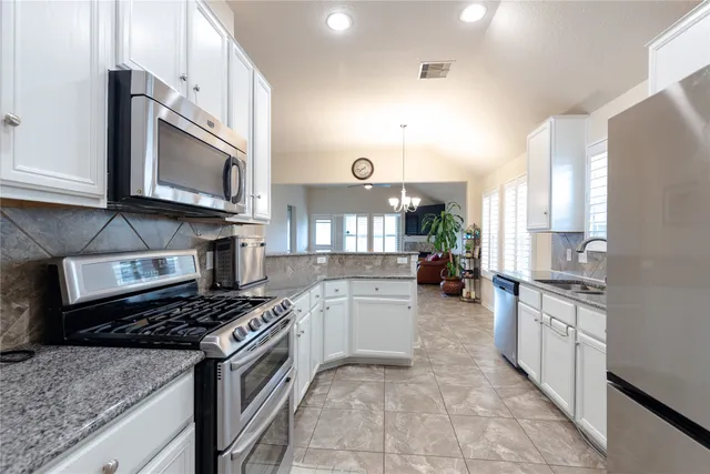 a kitchen with stainless steel appliances granite countertop a stove top oven a sink dishwasher and cabinets