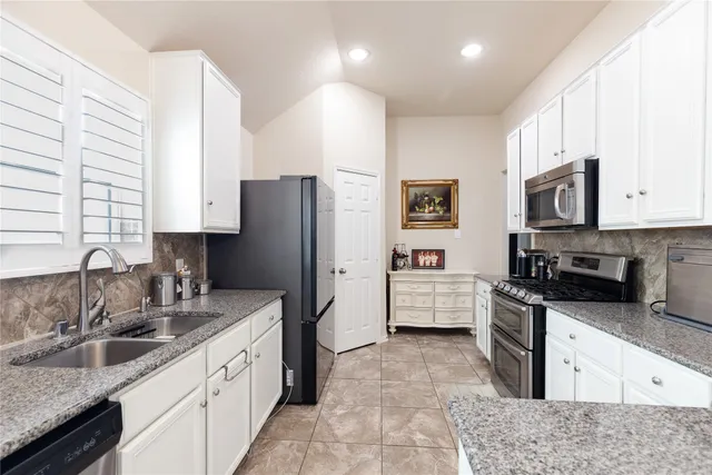 a large kitchen with stainless steel appliances granite countertop a sink a stove a refrigerator a washer and dryer