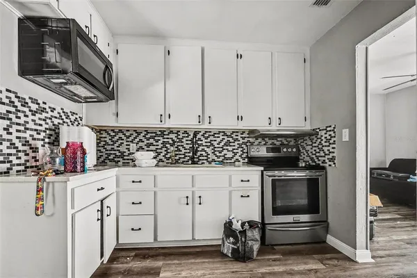 a kitchen with white cabinets and black appliances