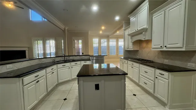 a kitchen with granite countertop white cabinets and a stove top oven