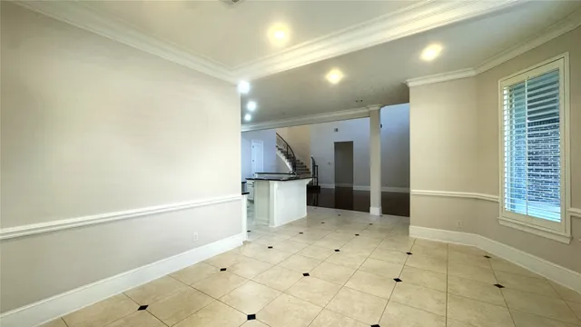 an empty room with chandelier fan and windows