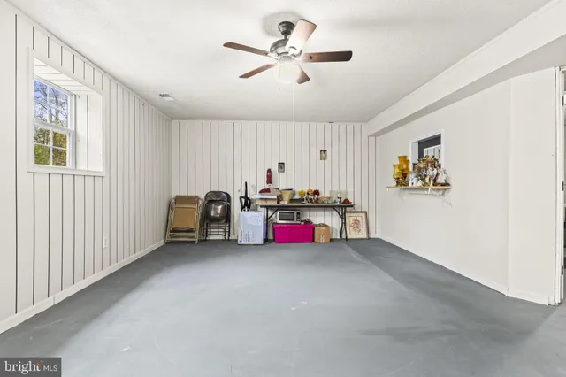 an empty room with chandelier fan and windows