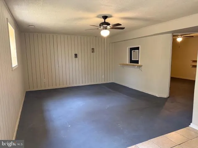 an empty room with windows and ceiling fan