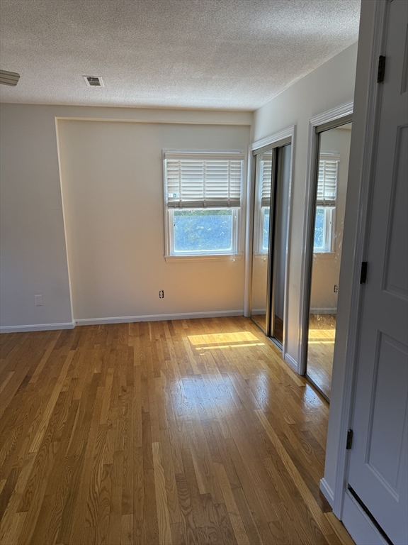 577 Adams Street, Unit D Milton, MA 02186 - Photo 11 of 11 an empty room with wooden floor and windows