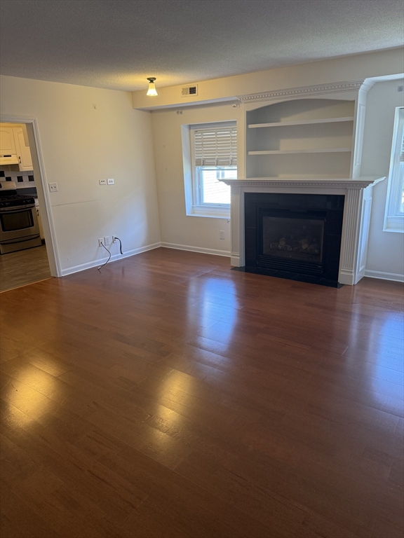 577 Adams Street, Unit D Milton, MA 02186 - Photo 3 of 11 an empty room with windows and fireplace