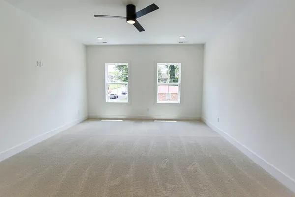an empty room with windows and fan