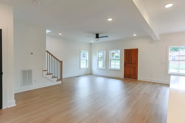 a view of an empty room with wooden floor and windows
