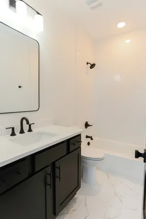 a bathroom with a bathtub sink vanity and mirror