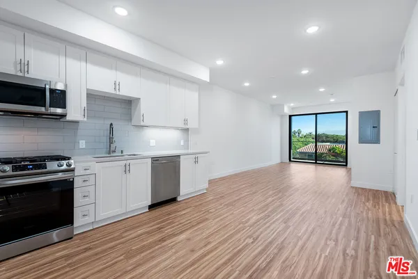 a kitchen with stainless steel appliances granite countertop a stove and a wooden floors