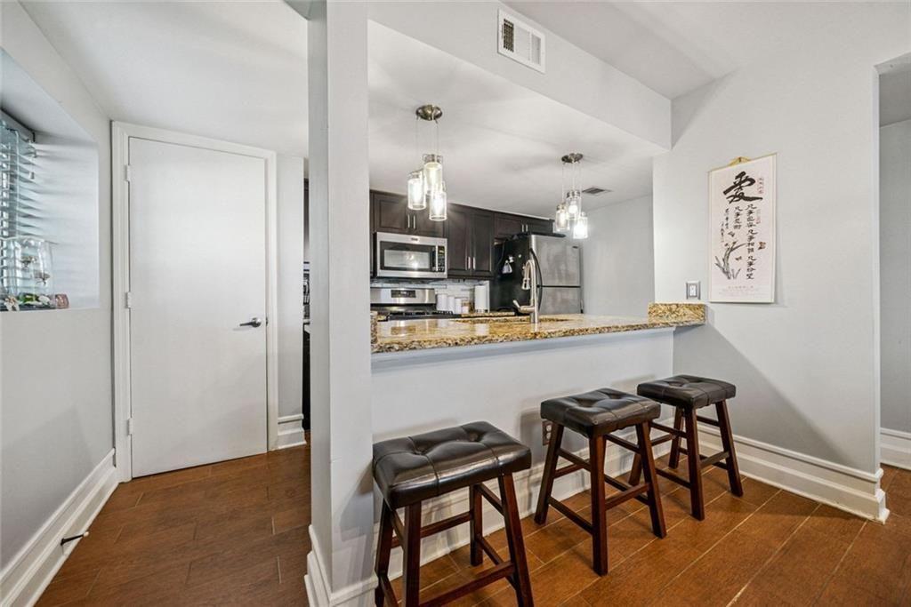 3048 Briarcliff Road Northeast, Unit 9 Atlanta, GA 30329 - Photo 5 of 30 a kitchen with stainless steel appliances kitchen island a table chairs in it and wooden floors