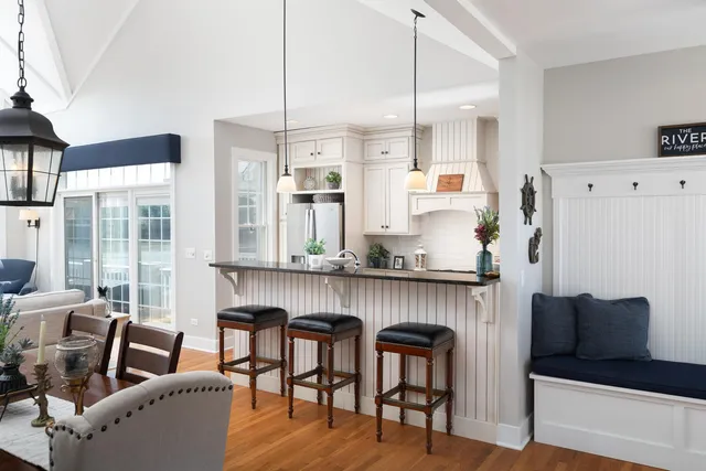 a kitchen with stainless steel appliances granite countertop a table chairs in it and wooden floors