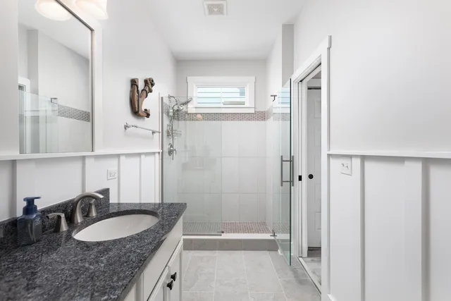 a bathroom with a granite countertop sink a mirror and a shower
