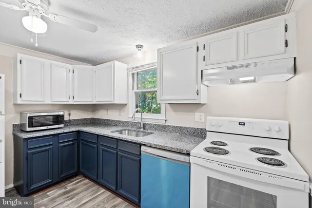 a kitchen with granite countertop a sink a stove and cabinets