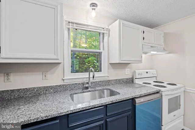 a kitchen with granite countertop a sink a stove and cabinets