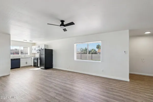 an empty room with wooden floor and a ceiling fan