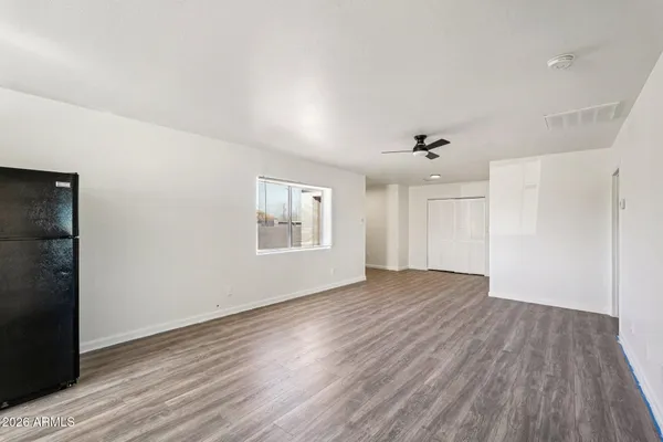 a view of an empty room with wooden floor and a window